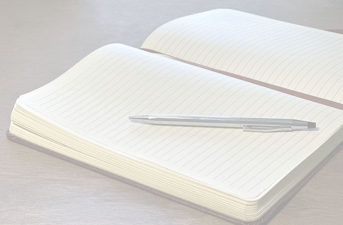 An open journal with a silver pen ready to use.